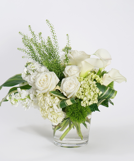 asymmetrical arrangement of white roses, hydrangea, and calla lilies with textural accenting greens