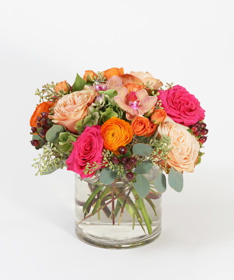 floral design of orange roses, hot pink ranunculus and berry vanda orchids with textural fall accents