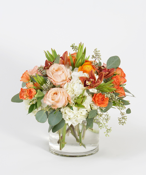 fall floral design featuring orange roses, peach roses, bronze orchids, and textural greens