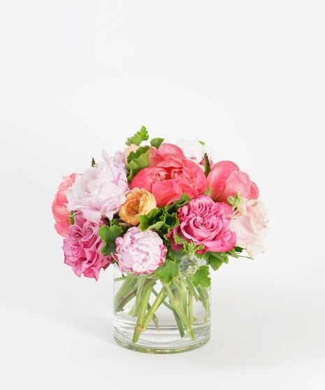 floral design featuring coral peonies, peach ranunculus, and pink roses