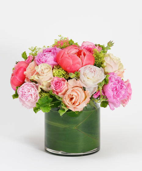 low and lush floral arrangement of pink peonies and pink roses accented with seasonal greens