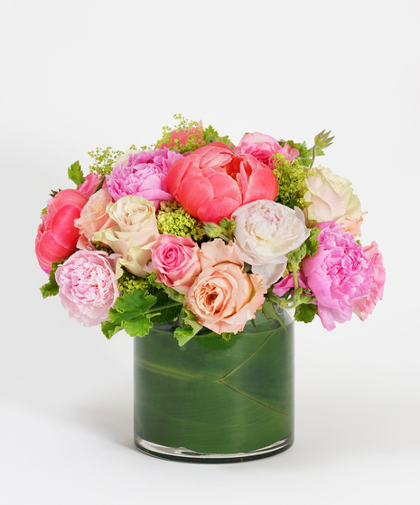 low and lush floral arrangement of pink peonies and pink roses accented with seasonal greens