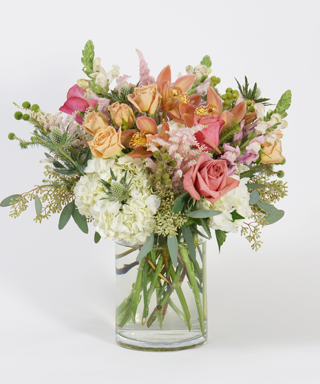 gardeny floral design of peach roses, white hydrangea, and lavender snapdragon with seasonal greens and textural accents.