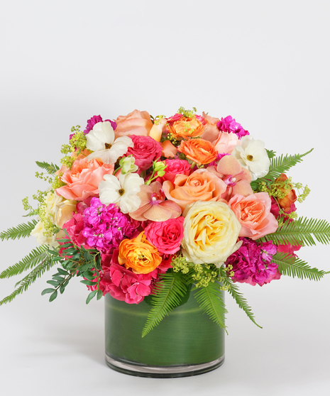 luxury floral design of hydrangea, roses, and orchids in shades of hot pink, magenta, orange, and green.
