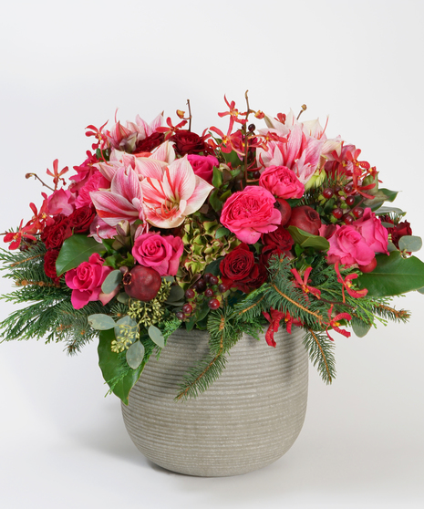 large holiday floral design of amaryllis, red roses, and two toned hydrangea accented with burgundy orchids, magnolia, and greens.