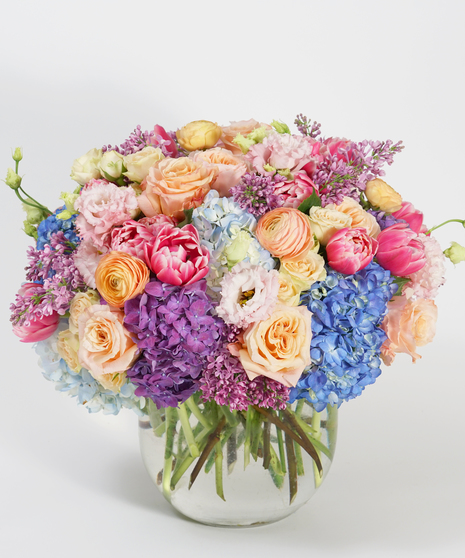 lush floral design of lilac, purple hydrangea, peach roses, and pink tulips