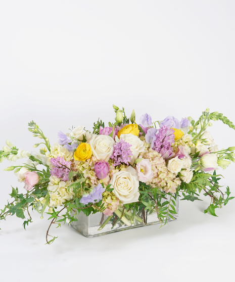 spring floral centerpiece of lavender sweet pea, cream roses, soft pink hydrangea, and seasonal greens
