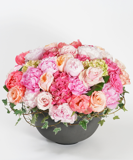 low and lush luxury spring floral design of coral peonies, pink hydrangea, and peach roses