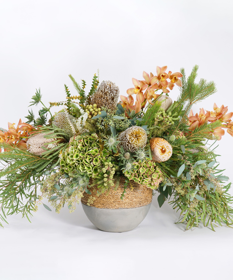 luxury floral arrangement of unique blooms and textural accents in a rustic stone bowl