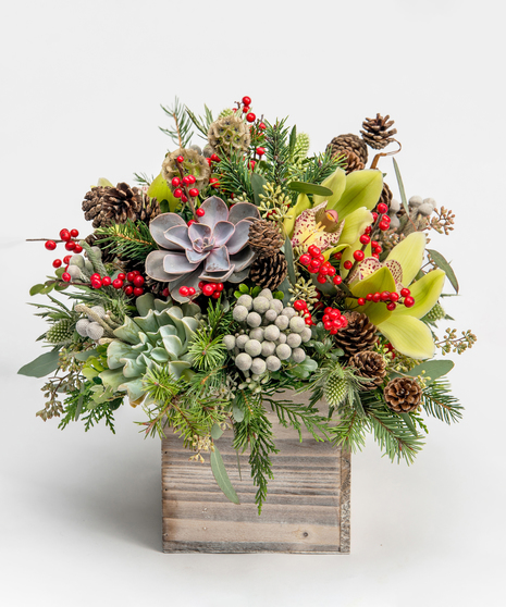 seasonal greens accented with succulents and red berries in a wooden cube