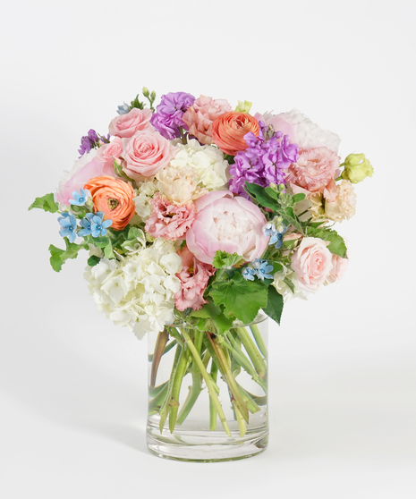 pastel toned floral design featuring pink tulips, peach roses, white hydrangea and lavender clematis