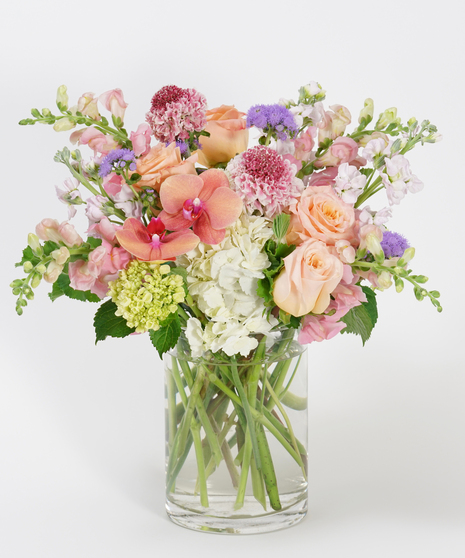 gardeny floral design of coral, peach and pink blooms featuring roses, scabiosa, snapdragon and orchids.