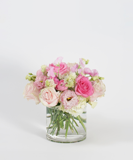 low and lush floral arrangement of peach roses, pink lisianthus, and white hydrangea