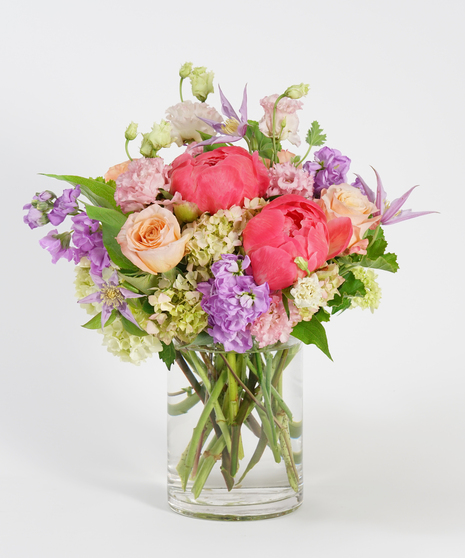 peach roses, coral peonies, lavender stock and pink hydrangea designed in a glass vase