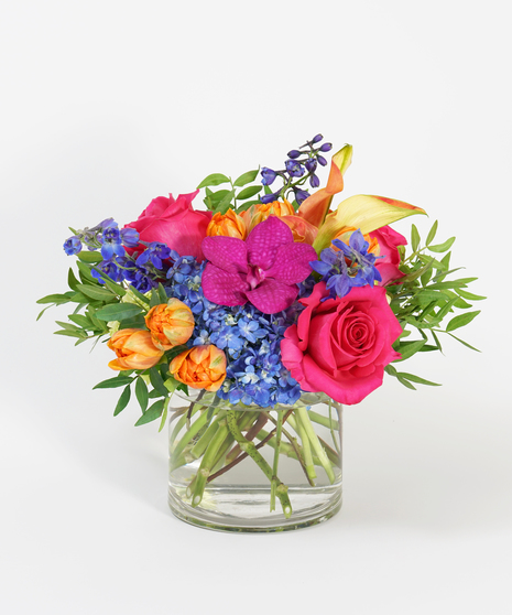 colorful arrangement of orange tulips, fuchsia orchids, and blue hydrangea