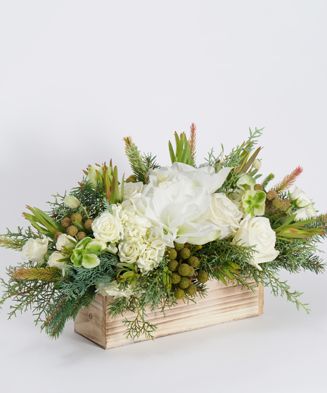 Holiday centerpiece of all white blooms and winter greens accents