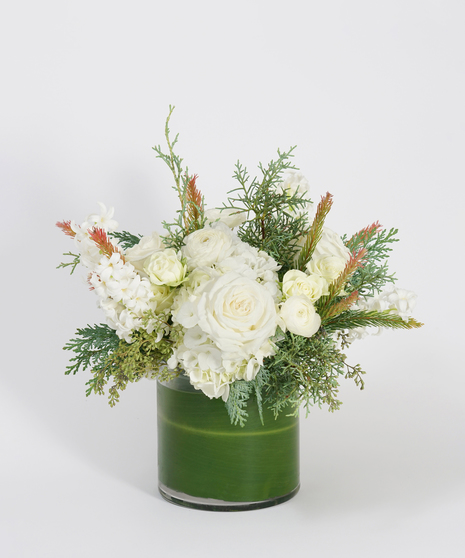 white winter floral arrangement with hydrangea and hyacinth accented with seasonal greens